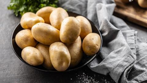 Raw potatoes in a black bowl