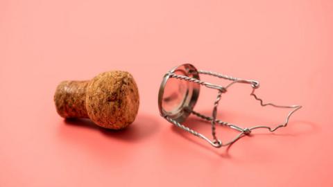 A cork sits next to a muselet.