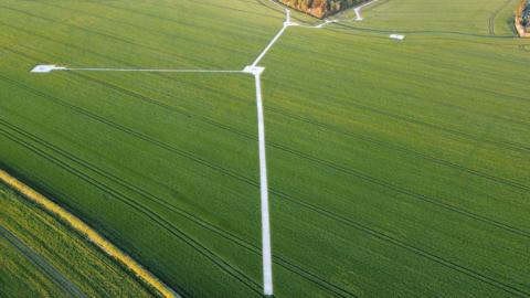 A very green and flat field which has silver coloured track laid across it in an inverted Y-shape. 