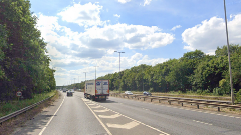 A general view of the eastbound carriageway of the A1139 Fletton Parkway. Vehicles can be seen travelling down both sides of the dual carriageway. The carriageway is lined with trees on either side. 