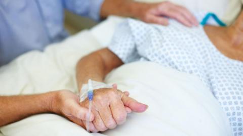 Woman in bed with hand being held