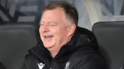 Mark Robins laughing in the Stoke dugout