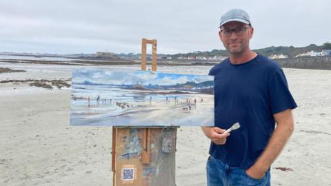 Tony Parsons with a painting on the beach