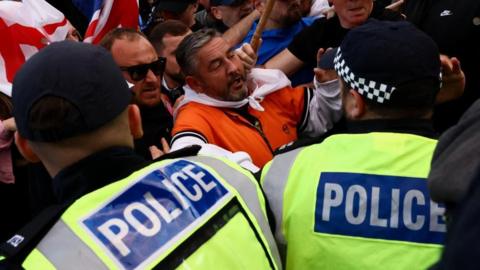 Protesters demonstrating an asylum hotel in Epping pushed up next to police officers in high vis jackets