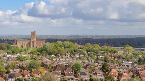 A Surrey town pictured from afar. It is leafy and green.