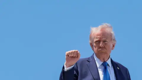 U.S. President Donald Trump makes a fist as he boards Air Force One while he departs Palm Beach International Airport en route to Joint Base Andrews, in West Palm Beach, Florida