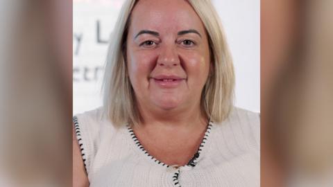A blonde woman with bobbed hair smiles at the camera