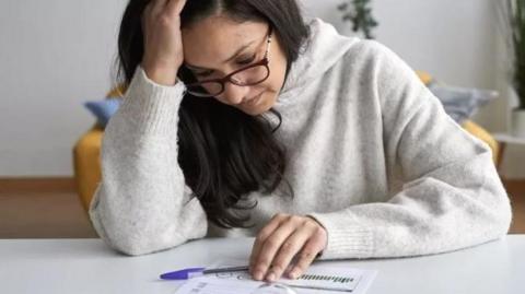 A woman looking anxiously at paperwork