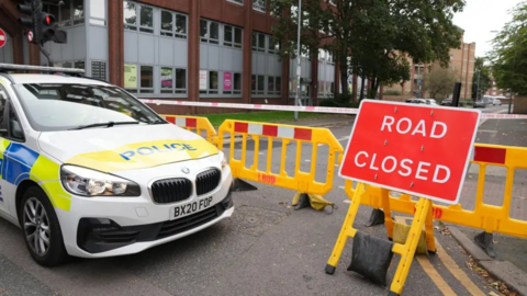 A police car and a red 'road closed' sign at the end of a street in Barking