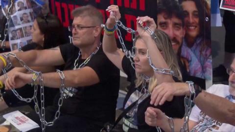 People sitting with chains around them, on the ground outside Benjamin Netanyahu's office