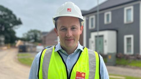 An image of Connor McCandless wearing a hi-vis jacket and a builders hat 