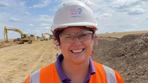 Regan Harris on a construction site, smiling and wearing a hard hat