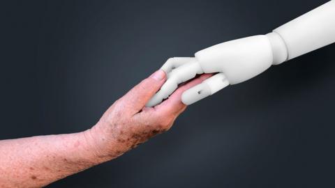 Old woman's hand holding a robot hand - stock photo
