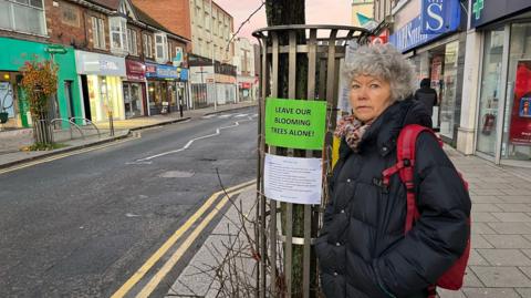 Sue Cooper beside a tree on Walton-on-Thames high street