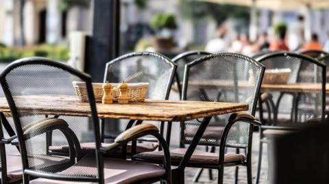 Outdoor tables and chairs. On the surface of none table is a basket and salt and pepper pots.
