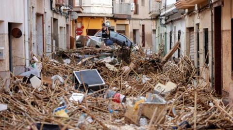 A resident walks over debris in the flood-hit municipality of Paiporta