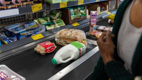 Eggs, bread, milk, and other food on a conveyor belt