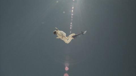 Photo of Felix Baumgartner's record-breaking and historic skydive in 2012. He is dressed in a white spacesuit and falling through blue sky - pictured from an angle below and with lens flares running through the centre of the image from the sun above.