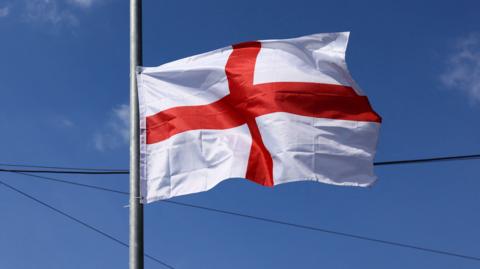 A close up of a the red and white St George's flag, hung on a flag pole.