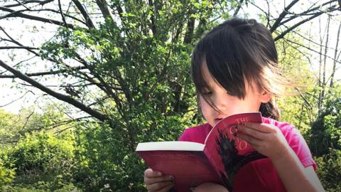 Young girl reading a book outside