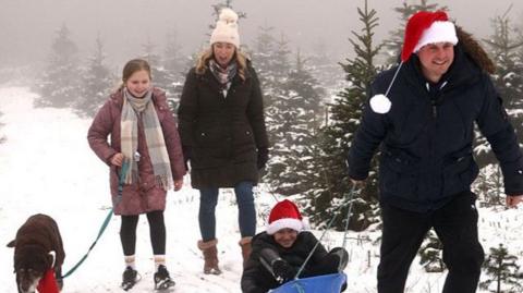 A family walk through the Bradgate Christmas Tree Farm near Newtown Linford after snowfall in Leicestershire, central England, on 3December 2023