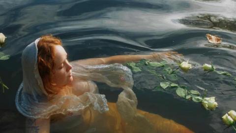 Meg is floating in the Avon with roses on the water.