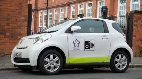 A small white car with a camera on top