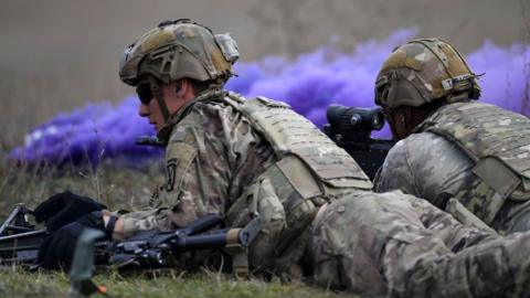 Soldiers lie on the ground with guns as they train in a Dacian Fall 2024 tactical training exercise held in NATO military base in Cincu, Romania, on 30 October 2024