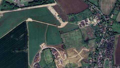 An aerial view of the land south of Eye Airfield where the new homes will be build. The landing strip can be seen at the top of the image, with other already built homes to the south.