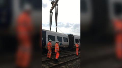 Derailed train being picked up by crane