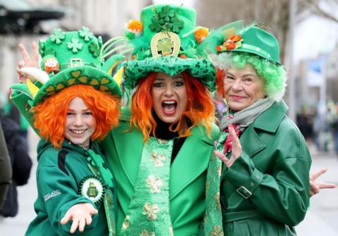 Three people wearing green outfits and orange wigs to celebrate St Patrick's Day in Dublin. 