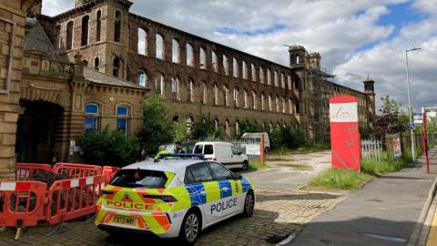 A police car parked outside Dalton Mills after a recent arson attack