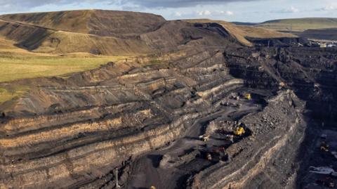 Golygfa o'r lofa glo brig pan oedd hi dal yn rhedeg. Mae offer diwydiannol yn waelod y llun gyda un o'r tomenni dadleuol yn uchel yn y cefndir. 