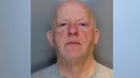 Mugshot of David Fletcher who is bald man and wearing a grey T-shirt. 