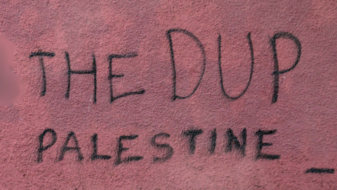 graffiti on red wall saying "the DUP palestine