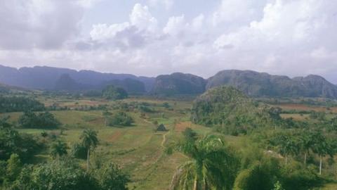 An aerial photograph of trees, hills and mountains on the horizon.