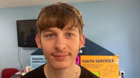 Damien standing by a series of blocks setting out topics for a youth debate