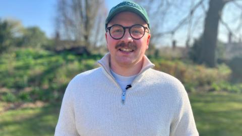30-year-old Sam, one of the attendants on the symposium, smiling for the camera outside.