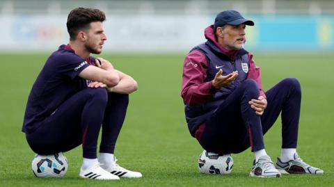 England boss Thomas Tuchel and Declan Rice during a training session sitting on footballs and talking