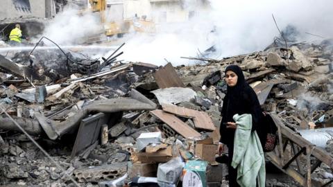 A woman looks for her belongings as she stands amidst the debris of a destroyed building, after a ceasefire between Israel and Iran-backed group Hezbollah took effect at 0200 GMT on Wednesday after U.S. President Joe Biden said both sides accepted an agreement brokered by the United States and France, in Tyre, Lebanon, November 27, 2024.