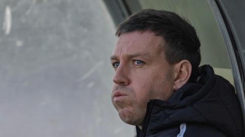 Gateshead manager Carl Magnay sat in the dugout during a game