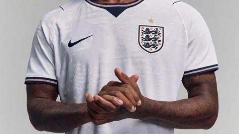 Marcus Rashford clasps his hands while modelling England's white Nike home shirt for the 2026 Fifa World Cup