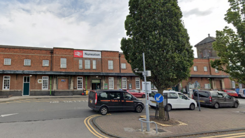 Nuneaton Railway Station, a brick building with a taxi rank in front and two trees