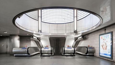 The station has a circular glass window above the escalators. 