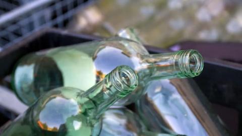 A close up view of several empty wine bottles in a plastic recycling box