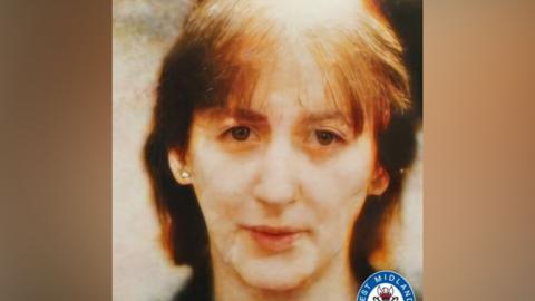 An old and blurry film photo of a women's face. She has brown hair.