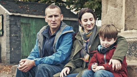 A couple and their child sat down outside.