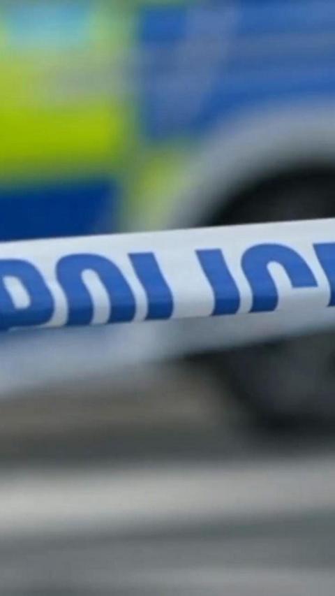 A close up of police tape and a police car