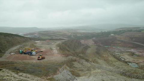 A general view of a mine showing machinery and dirt roads on a cloudy day.
