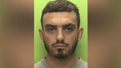 A mug shot of Connor Copse wearing a grey jumper on a green background